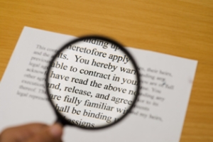 Magnifying glass on a contract with selective focus on the word "contract".